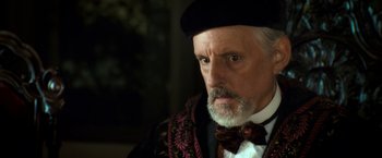 Movie still from “The Golden Compass” (2007), directed by Chris Weitz – An old man with a beard wearing a hat and a bow tie; Close Up shot, Over the shoulder angle