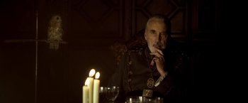 Movie still from “The Golden Compass” (2007), directed by Chris Weitz – An older man sitting in front of candles; Medium shot, Over the shoulder angle