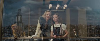 Movie still from “The Golden Compass” (2007), directed by Chris Weitz – A woman standing next to a young girl in front of a window; Medium shot, Low angle