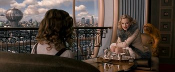 Movie still from “The Golden Compass” (2007), directed by Chris Weitz – A woman sitting in front of a window looking out at a city; Medium shot, Over the shoulder angle