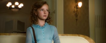 Movie still from “The Golden Compass” (2007), directed by Chris Weitz – A girl in a blue dress is looking at the camera; Close Up shot, Over the shoulder angle