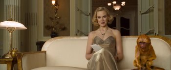 Movie still from “The Golden Compass” (2007), directed by Chris Weitz – A woman sitting on top of a couch holding a piece of paper; Medium shot, Over the shoulder angle