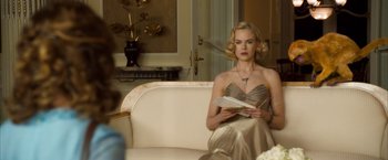 Movie still from “The Golden Compass” (2007), directed by Chris Weitz – A woman sitting on top of a couch holding a book; Medium shot, Over the shoulder angle