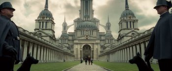 Movie still from “The Golden Compass” (2007), directed by Chris Weitz – People walking down a path in front of a large building; Extreme Wide shot, Low angle