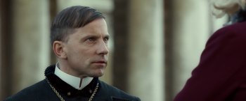 Movie still from “The Golden Compass” (2007), directed by Chris Weitz – A person wearing a priest's outfit; Close Up shot, Over the shoulder angle