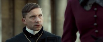 Movie still from “The Golden Compass” (2007), directed by Chris Weitz – A man wearing a chain looking at another man; Close Up shot, Over the shoulder angle