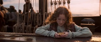 Movie still from “The Golden Compass” (2007), directed by Chris Weitz – A young girl looking at her cell phone on a boat; Close Up shot, High angle