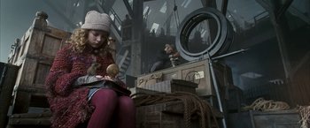 Movie still from “The Golden Compass” (2007), directed by Chris Weitz – A young girl sitting on top of a wooden platform; Medium shot, Low angle
