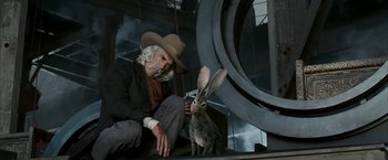 Movie still from “The Golden Compass” (2007), directed by Chris Weitz – An old man sitting next to a large rabbit; Medium shot, Low angle