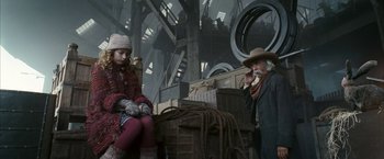 Movie still from “The Golden Compass” (2007), directed by Chris Weitz – A man and a girl sitting on a crate; Medium shot, Low angle