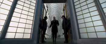 Movie still from “The Golden Compass” (2007), directed by Chris Weitz – A man standing in front of two other people; Wide shot, Low angle