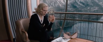 Movie still from “The Golden Compass” (2007), directed by Chris Weitz – A woman sitting on a window sill looking at a mirror; Medium shot, High angle