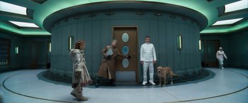 Movie still from “The Golden Compass” (2007), directed by Chris Weitz – Two men and a dog standing in front of a door; Wide shot, Low angle