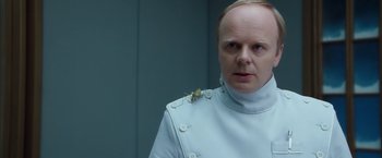 Movie still from “The Golden Compass” (2007), directed by Chris Weitz – A man in a white uniform with a bug on his shoulder; Close Up shot, Over the shoulder angle