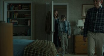 Movie still from “The Goldfinch” (2019), directed by John Crowley – A woman and a young boy standing in front of a bedroom door; Wide shot, Over the shoulder angle