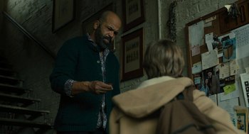 Movie still from “The Goldfinch” (2019), directed by John Crowley – A man standing next to another man in a room; Medium shot, Low angle