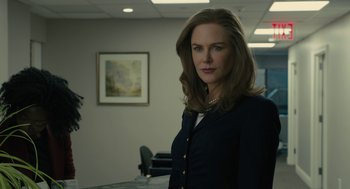 Movie still from “The Goldfinch” (2019), directed by John Crowley – A woman standing in a room wearing a suit and tie; Medium shot, Over the shoulder angle