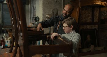 Movie still from “The Goldfinch” (2019), directed by John Crowley – A man and a boy working together on a piece of furniture; Medium shot, High angle