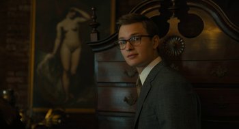 Movie still from “The Goldfinch” (2019), directed by John Crowley – A man in a suit standing in front of a dresser; Close Up shot, Low angle