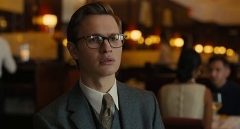 Movie still from “The Goldfinch” (2019), directed by John Crowley – A man in a suit and tie wearing glasses; Close Up shot, Low angle