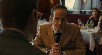Movie still from “The Goldfinch” (2019), directed by John Crowley – An older man sitting at a table in a suit; Close Up shot, Over the shoulder angle
