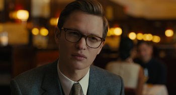 Movie still from “The Goldfinch” (2019), directed by John Crowley – A man in a suit and tie wearing glasses; Close Up shot, Over the shoulder angle
