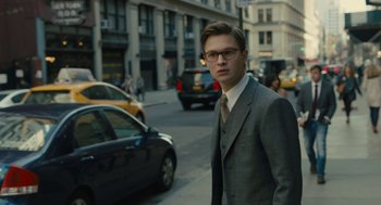 Movie still from “The Goldfinch” (2019), directed by John Crowley – A man in a suit and tie standing on the side of the street; Medium shot, Over the shoulder angle