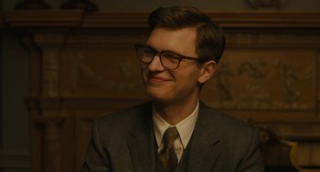 Movie still from “The Goldfinch” (2019), directed by John Crowley – A man wearing a suit and tie smiling; Close Up shot, Over the shoulder angle