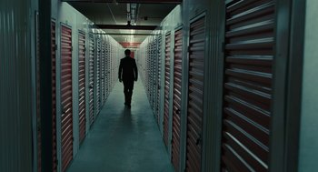 Movie still from “The Goldfinch” (2019), directed by John Crowley – A man walking down a hallway in a storage unit; Extreme Wide shot, Low angle