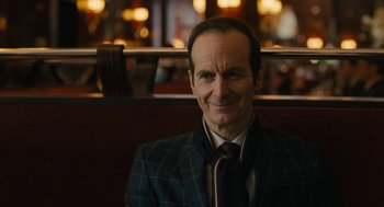 Movie still from “The Goldfinch” (2019), directed by John Crowley – A man in a suit and tie sitting on a bench; Close Up shot, Over the shoulder angle