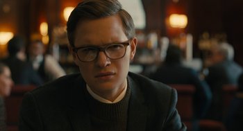 Movie still from “The Goldfinch” (2019), directed by John Crowley – A man in a suit and eyeglasses sitting at a table; Close Up shot, Over the shoulder angle