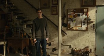 Movie still from “The Goldfinch” (2019), directed by John Crowley – A man standing in front of some stairs; Wide shot, High angle