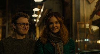 Movie still from “The Goldfinch” (2019), directed by John Crowley – A woman in a green jacket standing next to a man in glasses; Close Up shot, Over the shoulder angle