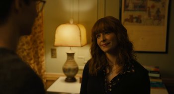 Movie still from “The Goldfinch” (2019), directed by John Crowley – A woman standing in front of a lamp in a room; Close Up shot, Over the shoulder angle