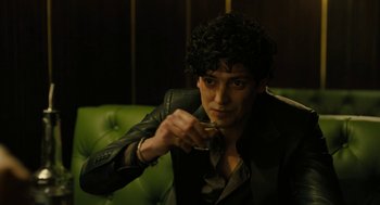 Movie still from “The Goldfinch” (2019), directed by John Crowley – A man sitting on top of a couch holding a wine glass; Close Up shot, Over the shoulder angle