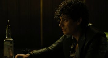 Movie still from “The Goldfinch” (2019), directed by John Crowley – A man with curly hair wearing a suit and tie; Close Up shot, High angle