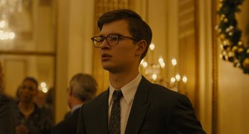 Movie still from “The Goldfinch” (2019), directed by John Crowley – A man in a suit and tie wearing glasses; Close Up shot, Low angle