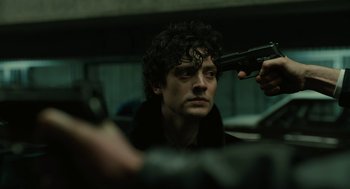 Movie still from “The Goldfinch” (2019), directed by John Crowley – A man holding a gun in front of a mirror; Close Up shot, Over the shoulder angle