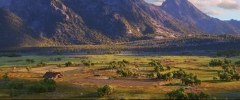Movie still from “The Good Dinosaur” (2015), directed by Peter Sohn – A large open field with trees and mountains in the background; Extreme Wide shot, High angle