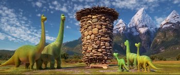 Movie still from “The Good Dinosaur” (2015), directed by Peter Sohn – A group of dinosaurs standing next to each other in front of a pile of rocks; Wide shot, Low angle