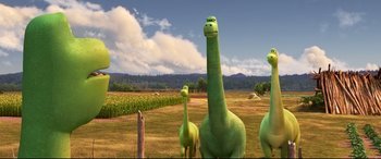 Movie still from “The Good Dinosaur” (2015), directed by Peter Sohn – A group of green dinosaurs standing in a grassy field; Extreme Wide shot, High angle