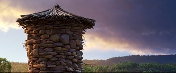 Movie still from “The Good Dinosaur” (2015), directed by Peter Sohn – A building made out of rocks with a thatched roof; Wide shot, Low angle