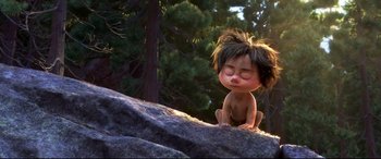 Movie still from “The Good Dinosaur” (2015), directed by Peter Sohn – An animated character sitting on top of a rock in a forest; Wide shot, High angle
