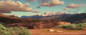 Movie still from “The Good Dinosaur” (2015), directed by Peter Sohn – A view of a mountain range with a cloudy sky above it; Extreme Wide shot, High angle