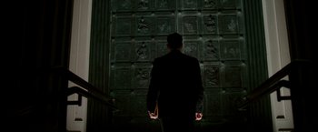 Movie still from “The Good Shepherd” (2006), directed by Robert De Niro – A man standing in front of a wall of statues; Wide shot, Low angle