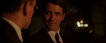 Movie still from “The Good Shepherd” (2006), directed by Robert De Niro – A man in a suit and tie smiling for the camera; Close Up shot, Over the shoulder angle