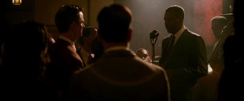 Movie still from “The Good Shepherd” (2006), directed by Robert De Niro – A group of men standing around a microphone in a room; Medium shot, Over the shoulder angle