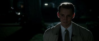 Movie still from “The Good Shepherd” (2006), directed by Robert De Niro – A man wearing a suit and tie standing in the dark; Close Up shot, Over the shoulder angle