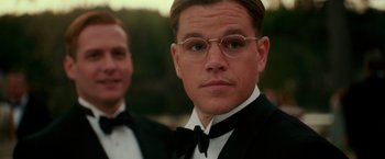 Movie still from “The Good Shepherd” (2006), directed by Robert De Niro – A person wearing glasses and a suit; Close Up shot, Over the shoulder angle