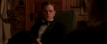 Movie still from “The Good Shepherd” (2006), directed by Robert De Niro – Matt damon in a suit and tie sitting in a chair in a room; Medium shot, Low angle